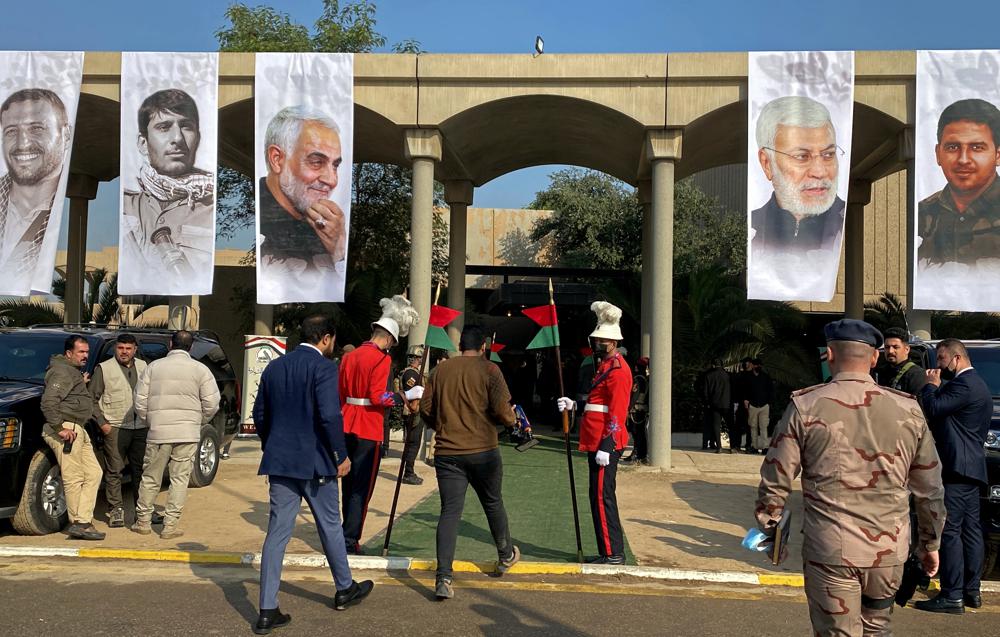 Mourners and security forces attend a ceremony to mark the second anniversary of the deaths of General Qassim Soleimani, third photo from left, and and Abu Mahdi al-Muhandis, second photo from right, in Baghdad's Green Zone, Iraq, Jan 5, 2022. 